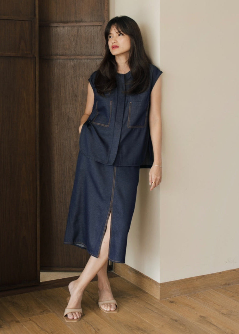 Woman in a navy blue dress standing against a wooden door.