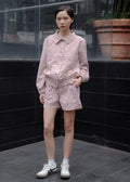 Person wearing a pink outfit standing against a black tiled wall.