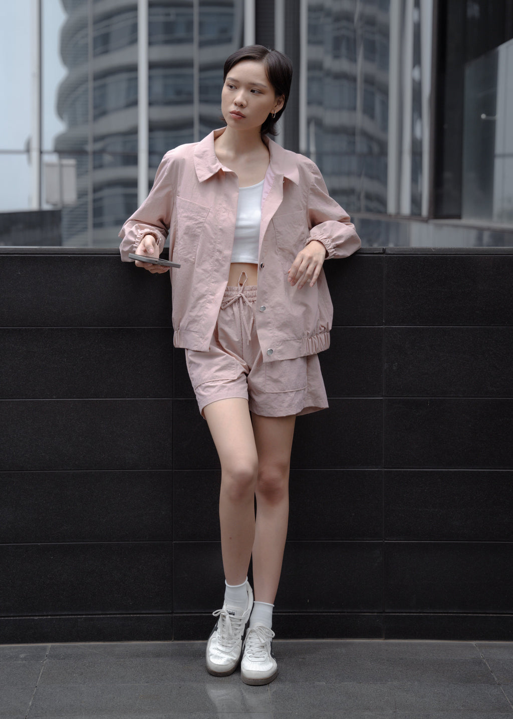 Woman in a pink outfit standing against a modern building.