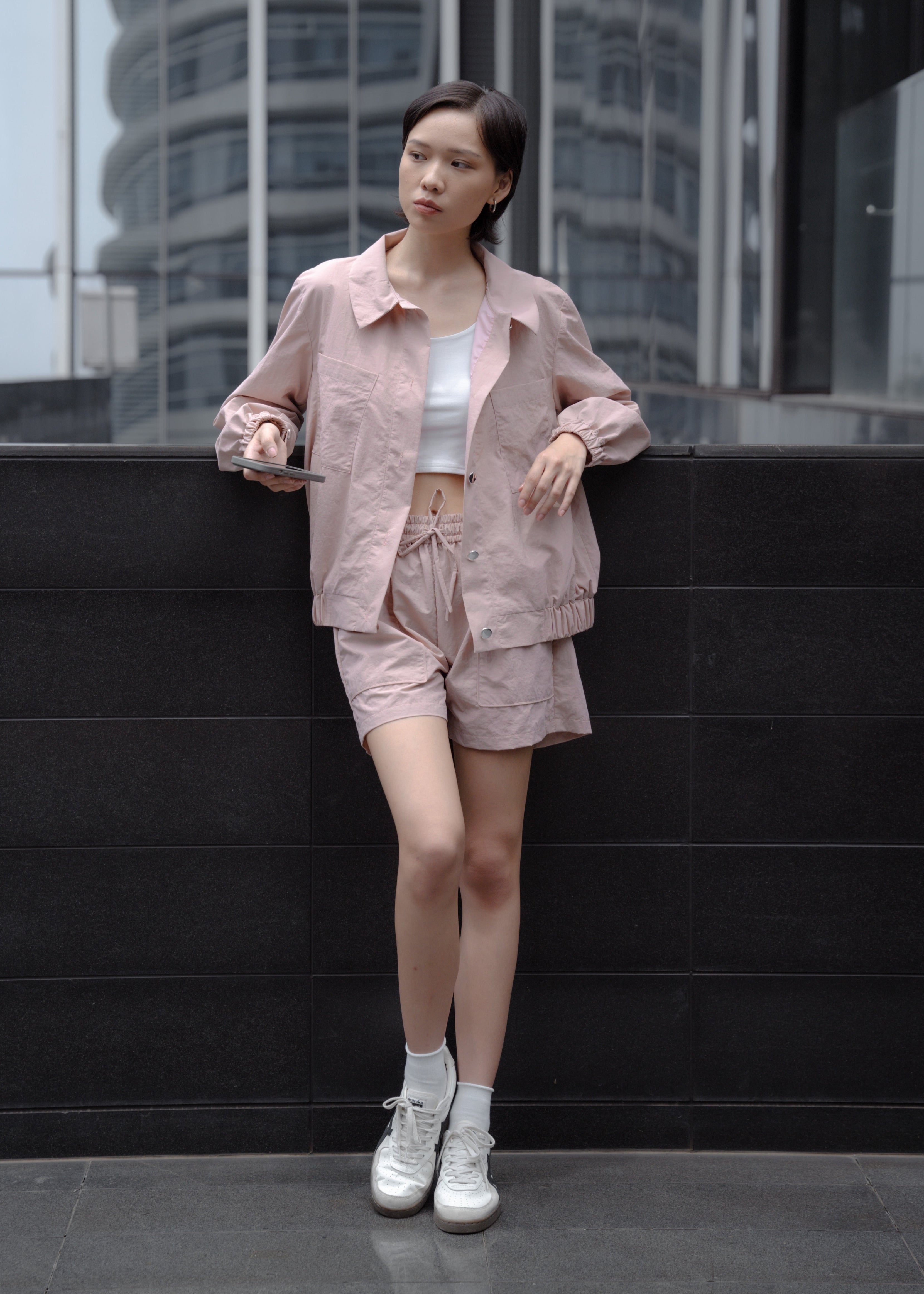 Woman in a pink outfit standing against a modern building.