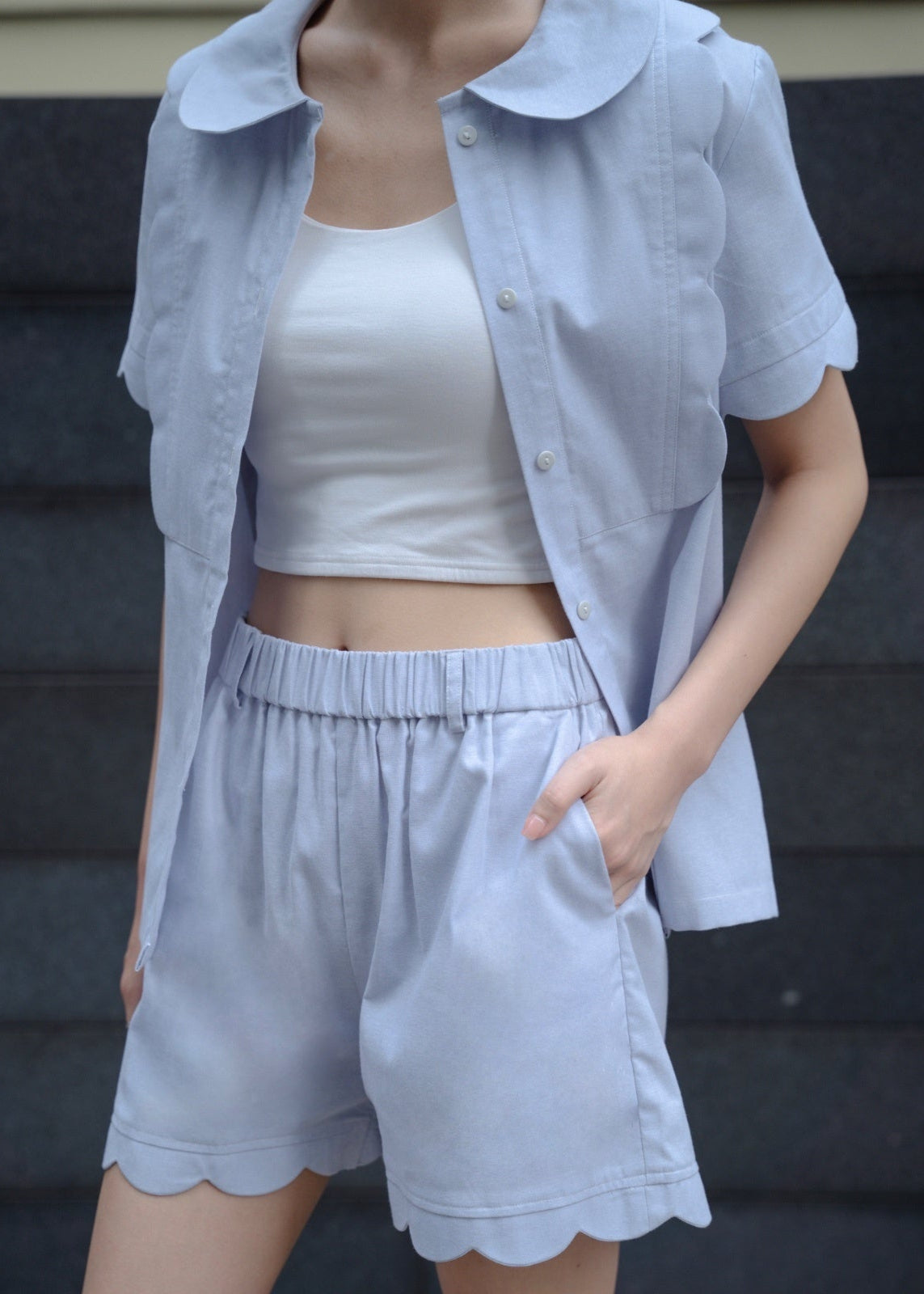 Person wearing a light blue outfit with a white top and shorts against a dark background