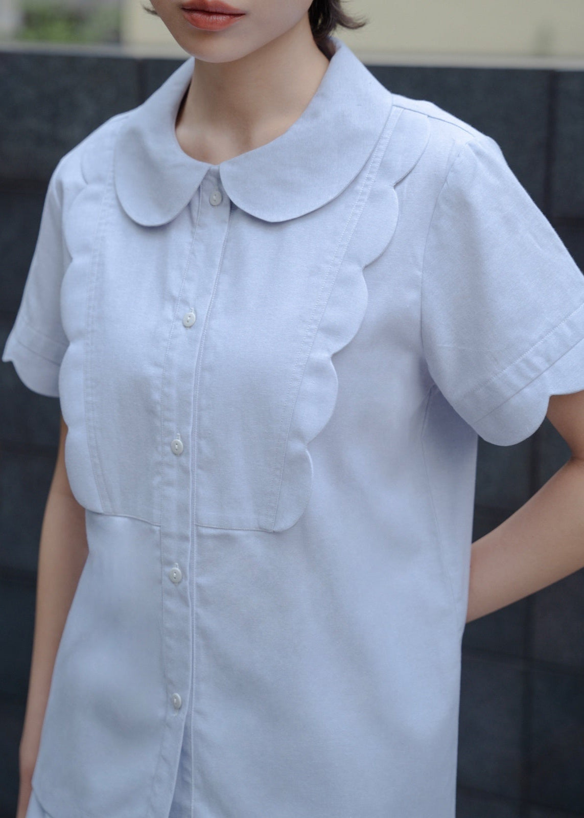 Light blue dress with a collar worn by a person against a dark background