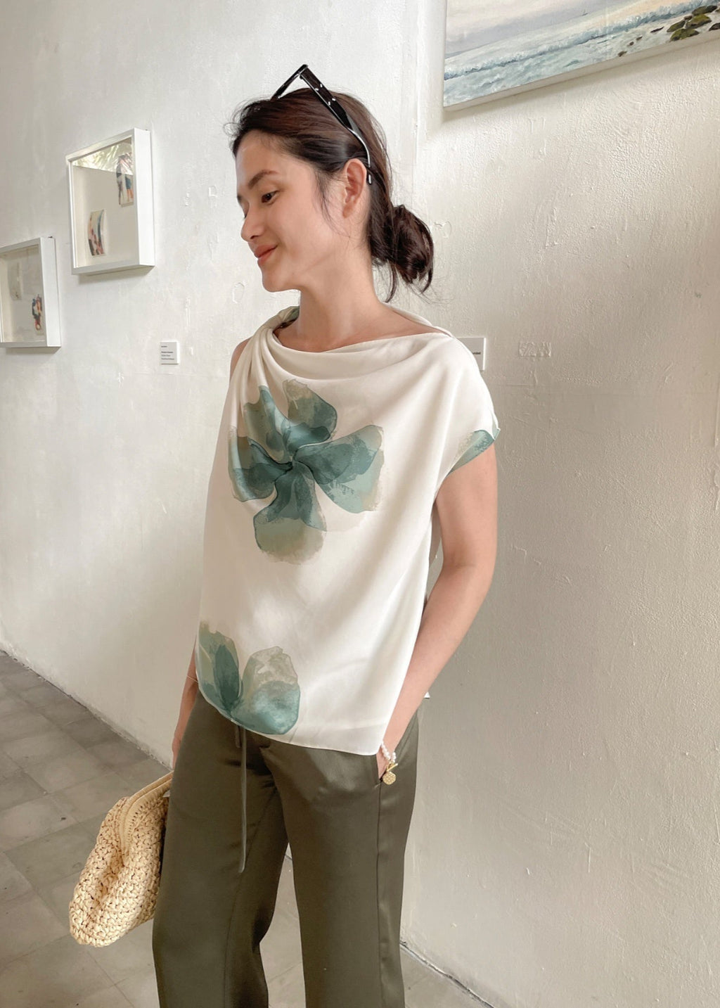 Woman wearing a white blouse with green floral patterns in an art gallery.