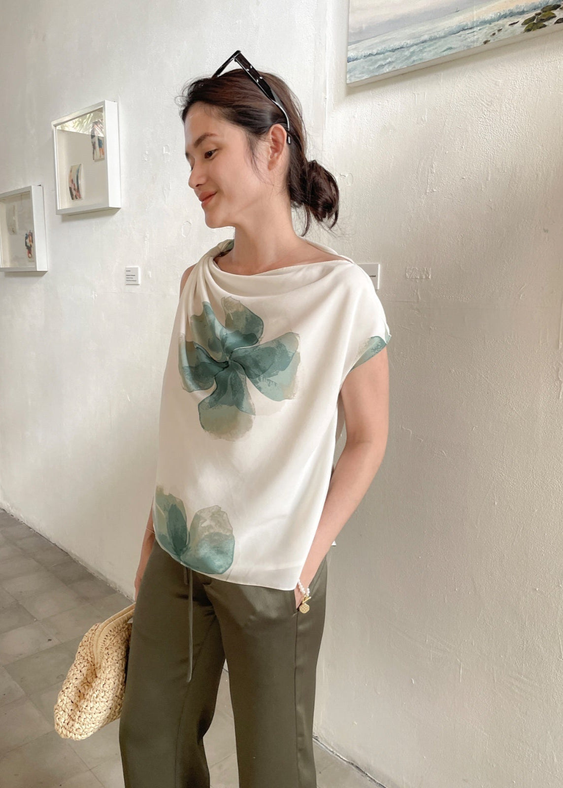 Woman wearing a white blouse with green floral patterns in an art gallery.