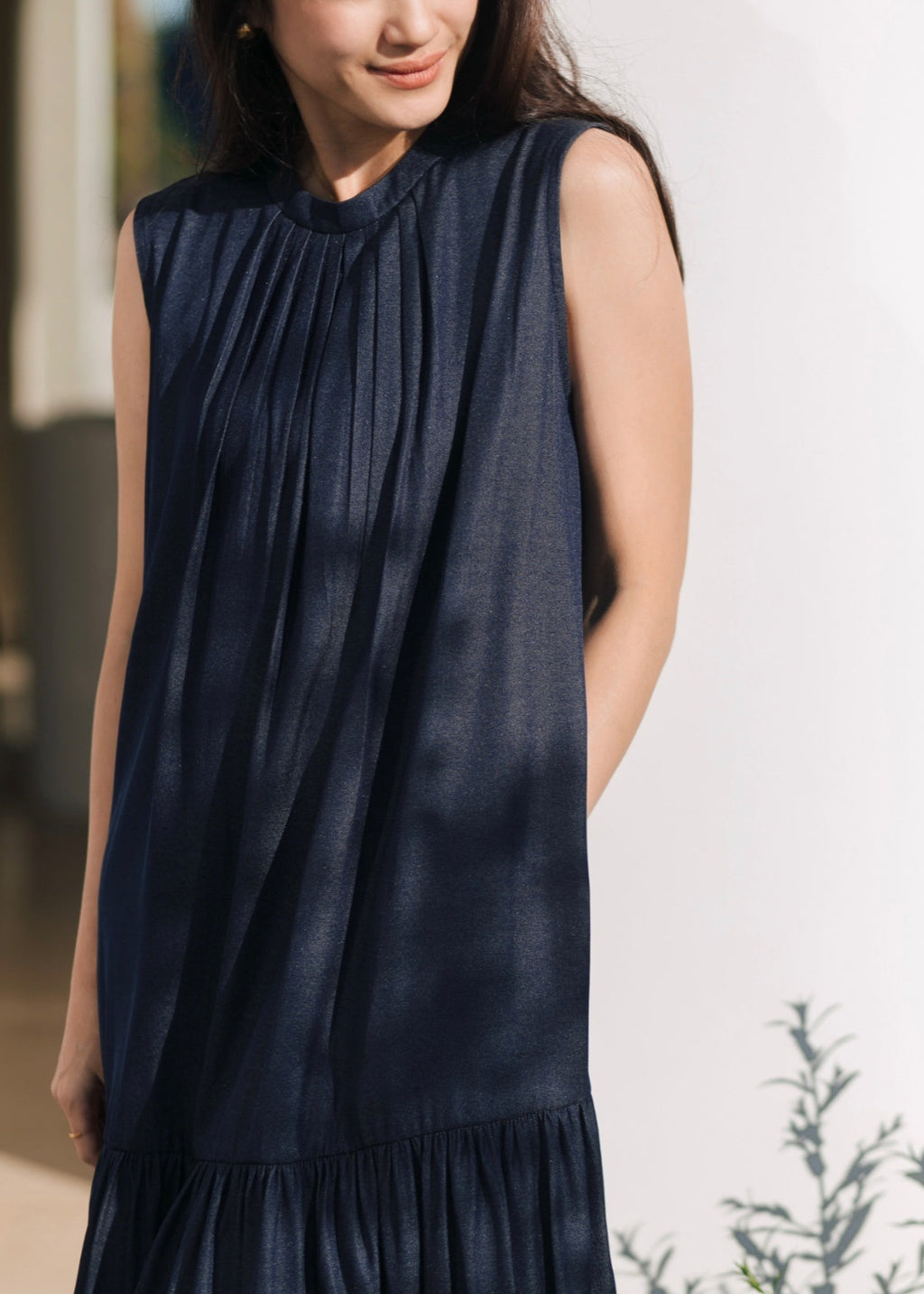 Woman wearing a sleeveless navy dress against a blurred background
