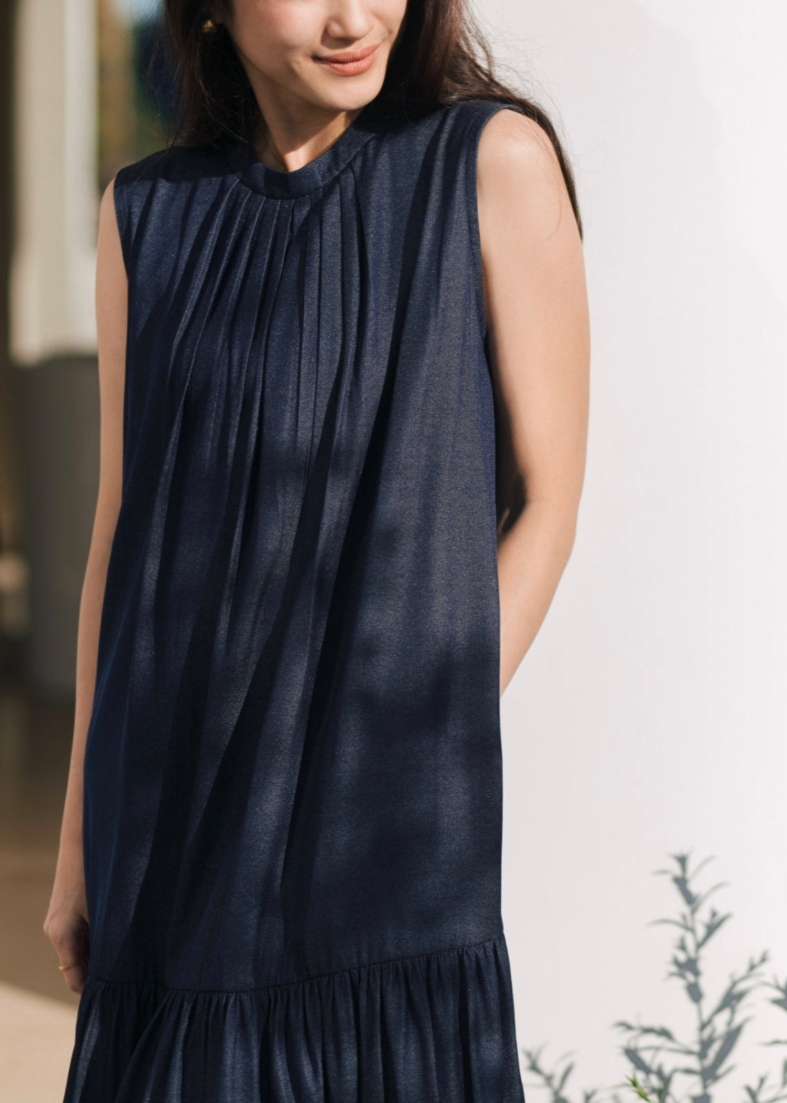 Woman wearing a sleeveless navy dress against a blurred background