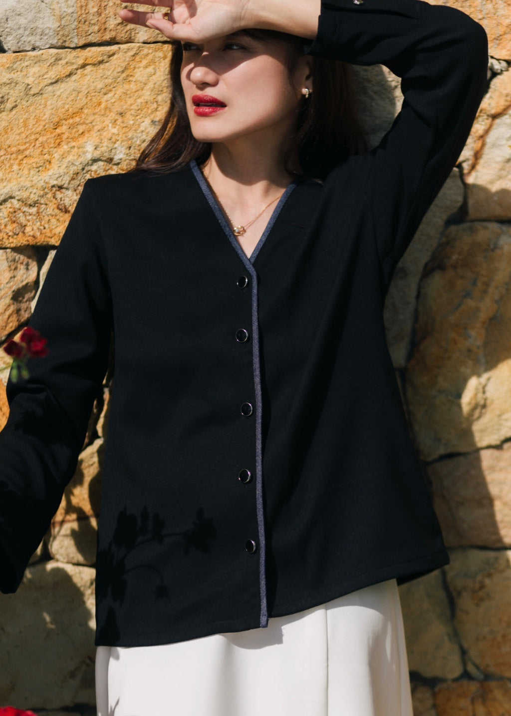 Woman wearing a black cardigan against a stone wall