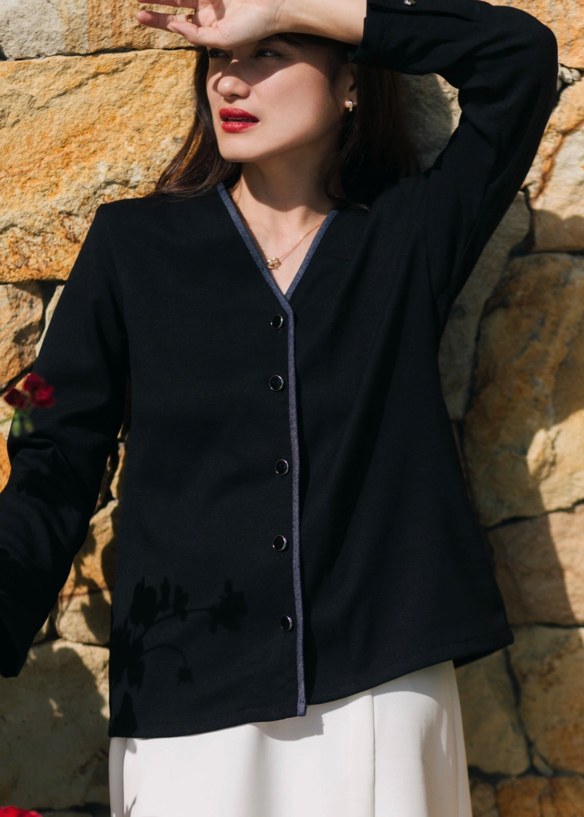 Woman wearing a black cardigan against a stone wall