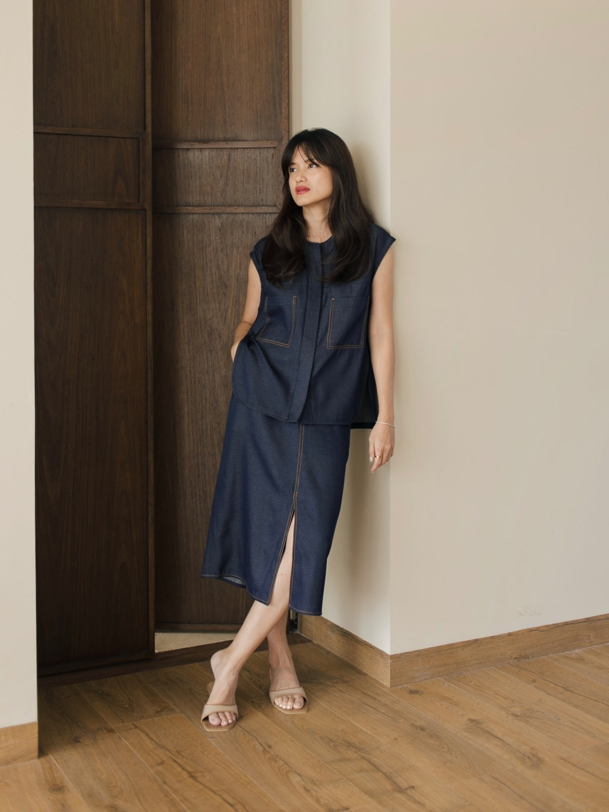 Woman in a navy blue dress standing against a wooden door.