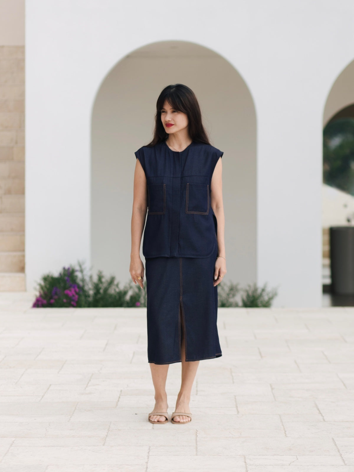 Woman wearing a navy blue outfit standing in front of a white archway.