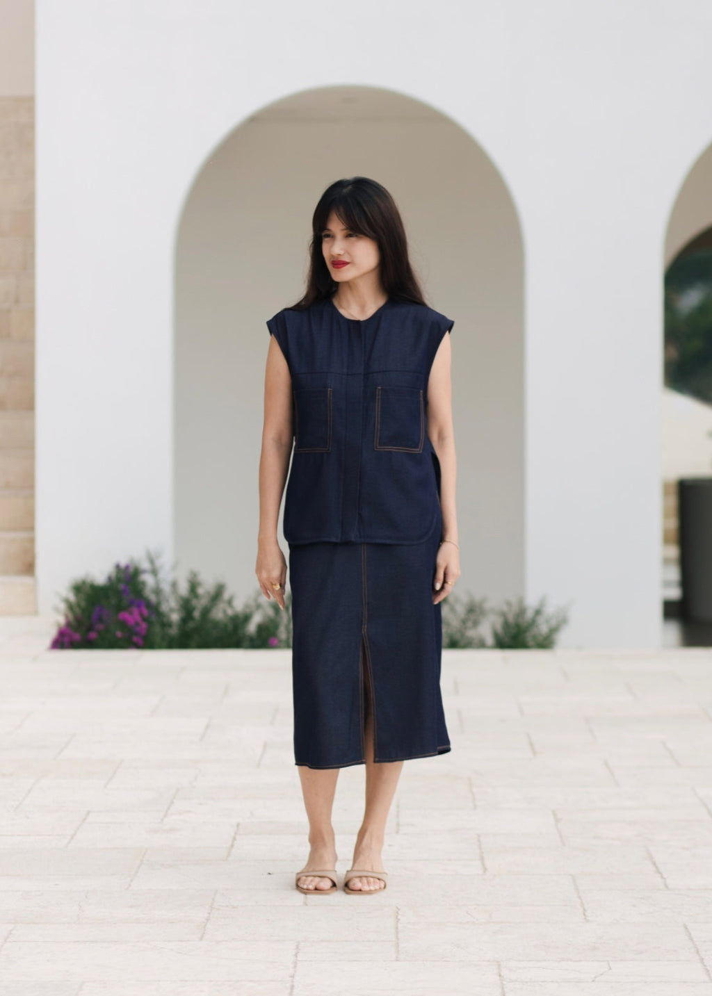 Woman wearing a navy blue outfit standing in front of a white archway.