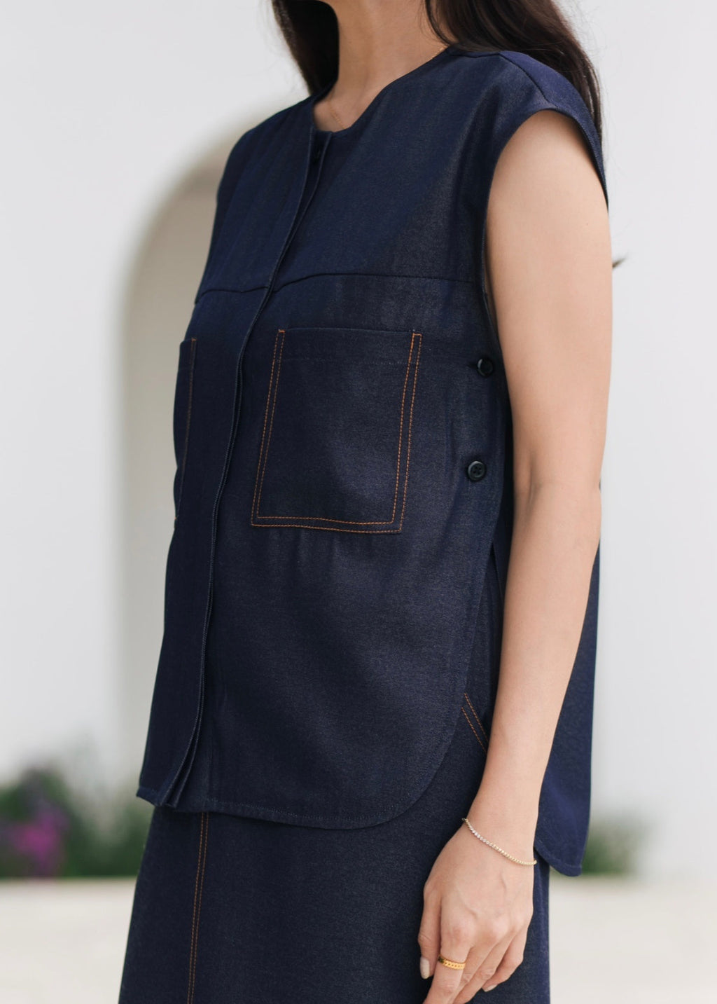 Person wearing a navy blue sleeveless jacket against a white background