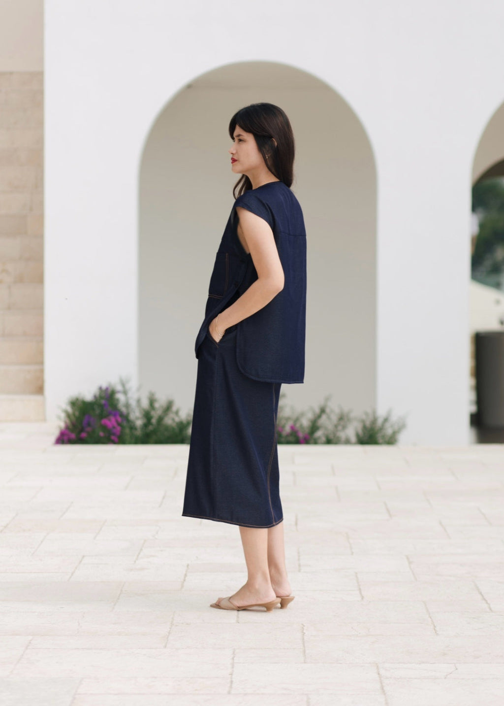 Woman wearing a navy blue outfit standing in front of an archway.